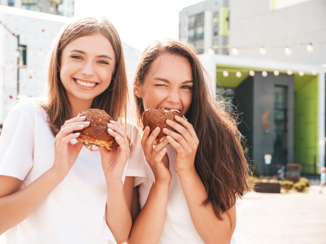 Das Bild zeigt zwei Frauen, die Burger auf einem Street Food Markt in Hamburg essen.