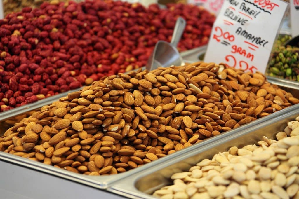 Das Bild zeigt Nüsse, die an einem Stand auf einem Wochenmarkt angeboten werden und dient als Titelbild für das Thema "Nüsse: Sorten, Vitamine, Ernte und Rezepte".