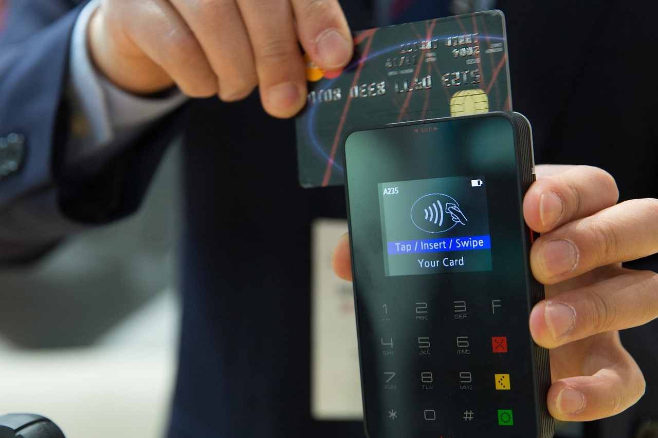Das Bild zeigt wie mit einer Kreditkarte an einem Kartenterminal bezahlt wird und dient als Titelbild für das Thema "Vergleich mobiler Kassensysteme und Kartenterminals".